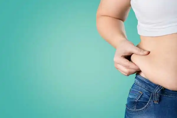 Image of woman pinching her love handles to show weight gain Stamford